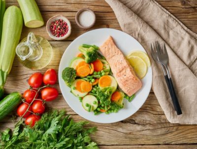 ein Teller mit Lachs, Brokkoli, Tomaten, Gurken und.